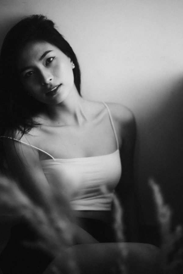 Black and white of young contemplative ethnic female in trendy wear looking at camera with tilted head Mobile 4K