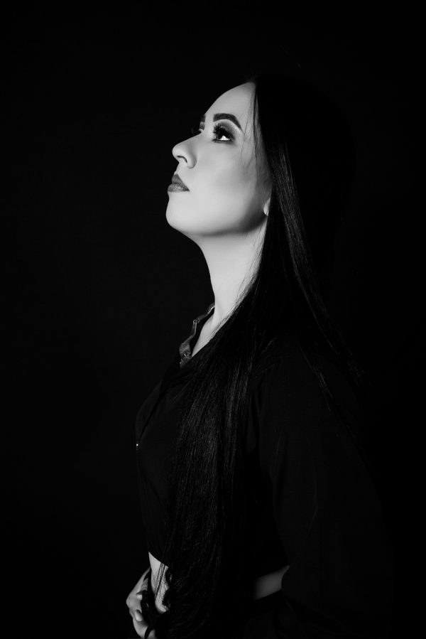 Black and white profile portrait of a woman in a studio setting, looking upwards. Mobile 4K