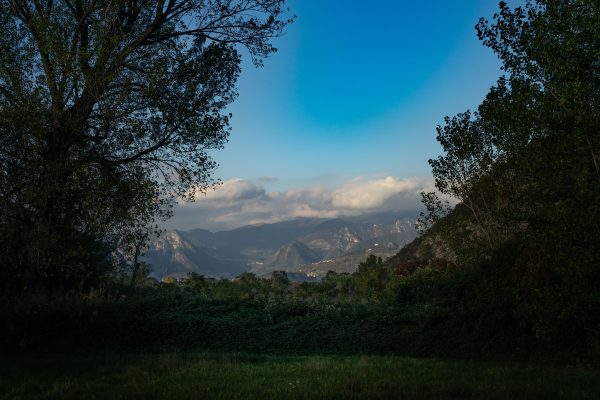 Breathtaking view of a mountain range surrounded by trees under a clear blue sky. Nature 4K