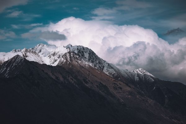 Breathtaking view of a snowcapped mountain range beneath a dramatic cloudy sky, perfect for travel inspiration. Nature 4K