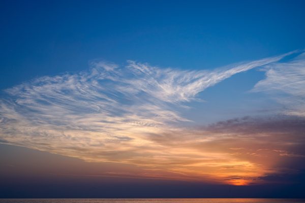 Breathtaking view of a sunset over the ocean, featuring vibrant colors and wispy clouds. Nature 4K
