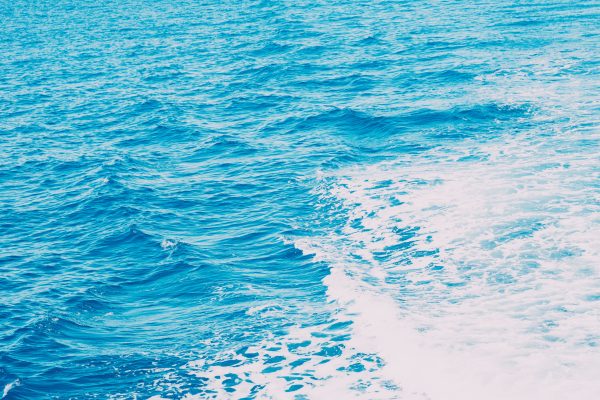 Bright blue ocean waves with white ship wake, showcasing the sea's dynamic beauty. Nature 4K