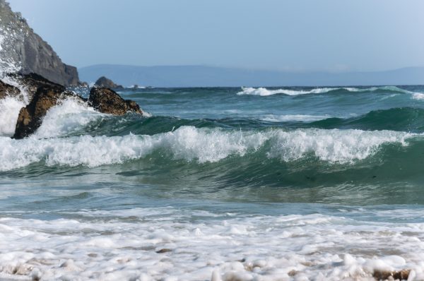 Captivating ocean waves hitting a rocky shore in County Kerry, Ireland, on a clear day. Nature 4K