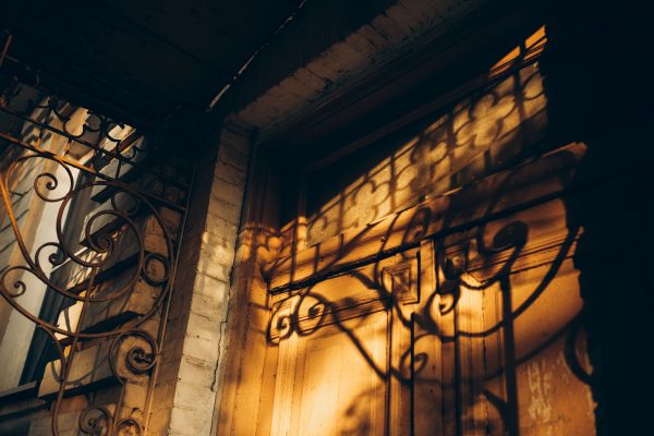 Captivating play of light and shadow on an ornate wrought iron gate at sunset. Dark 4K
