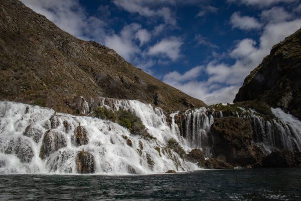 Captivating view of cascading waterfalls amidst stunning mountains under a cloudy blue sky. Nature 4K