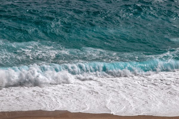 Captivating view of turquoise ocean waves crashing onto a golden sandy beach, showcasing nature's beauty. Nature 4K