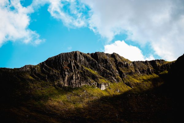 Captivating view of Welsh mountain peaks illuminated by sunlight, surrounded by vibrant blue sky and clouds. Nature 4K