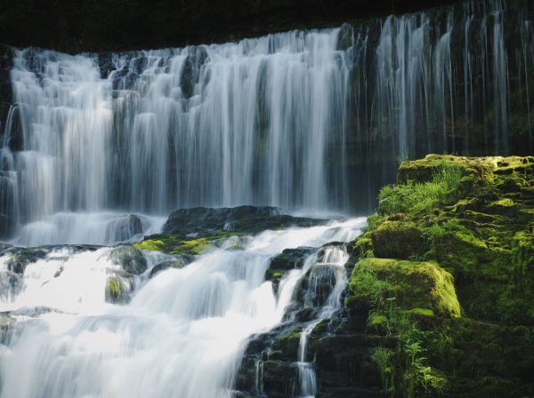 Captivating waterfall in Wales with lush moss and serene cascades. Nature 4K