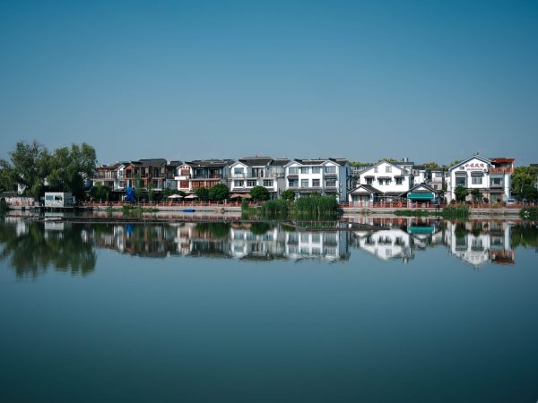 Charming traditional homes reflecting in calm lake waters under a clear blue sky. Nature 4K