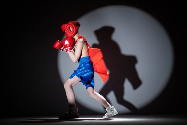 Child dressed as a superhero boxer shadow boxing under studio spotlight. Geek 4K