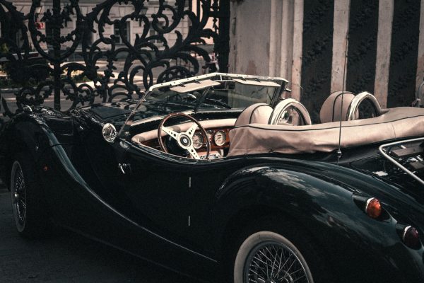 Classic roadster car parked by an intricate gate in Moscow, showcasing retro style and elegance. Voitures 4K