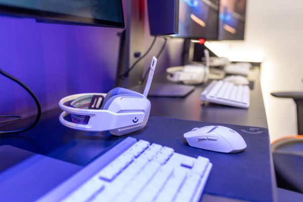 Close-up of a gaming setup featuring a white headset, computer mouse, and keyboard with a vivid lighting ambiance. Gaming 4K