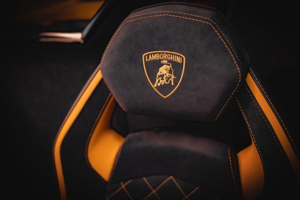 Close-up of a luxury Lamborghini seat interior design, featuring black and yellow leather stitching. Voitures 4K