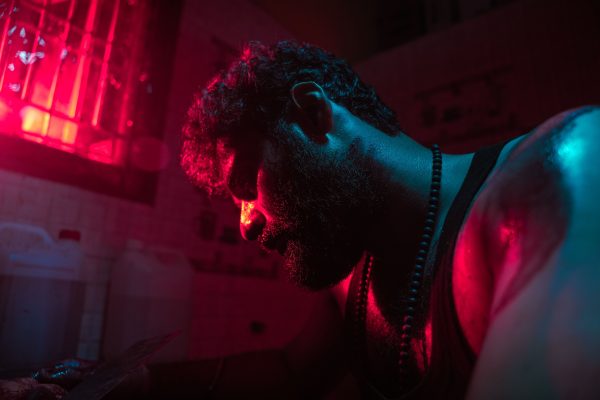 Close-up of a man's pensive pose under dramatic red lighting indoors. Dark 4K