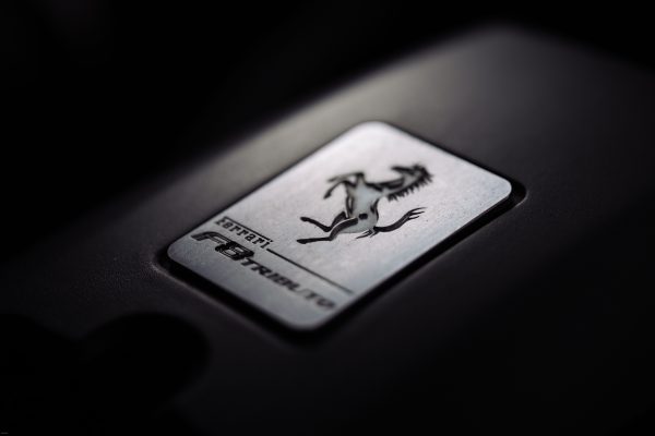 Close-up of a metallic car logo badge with a prancing horse, symbolizing luxury and speed. Voitures 4K