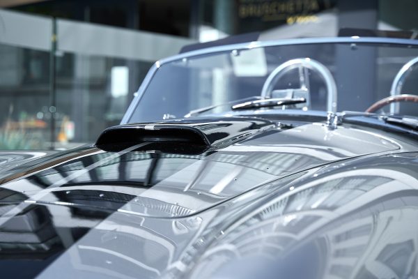 Close-up of a modern car hood reflecting light in a sunlit indoor setting. Voitures 4K