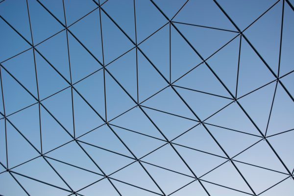 Close-up of a modern glass ceiling showcasing geometric patterns against a clear blue sky. Abstrait 4K