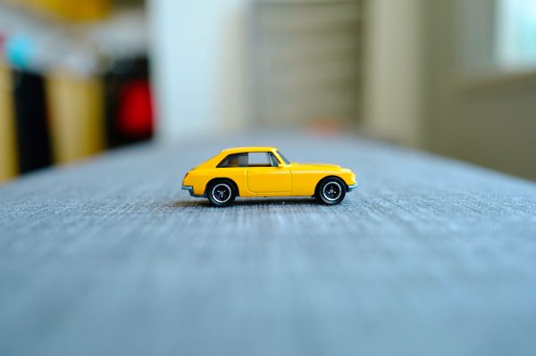 Close-up of a small yellow toy car placed on a table indoors, showcasing minimal design. Voitures 4K