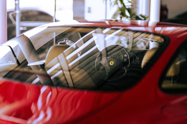 Close-up of a stylish red Ferrari interior with sunlight reflection in a showroom setting. Voitures 4K