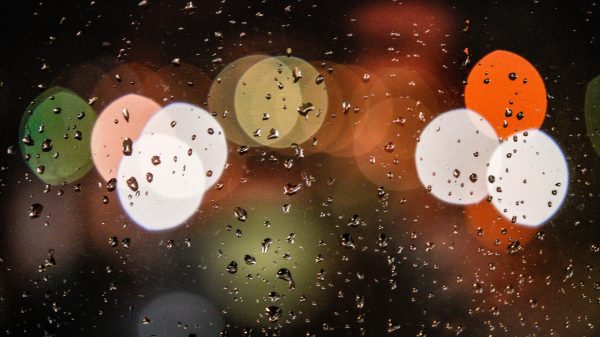 Close-up of raindrops on a window with colorful bokeh lights in the background, creating a dreamy effect. Voitures 4K