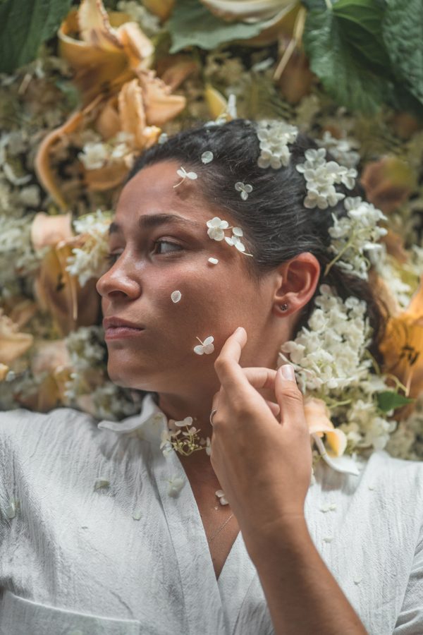 Close-up portrait of a woman lying on a bed of flowers, artistic and serene. Mobile 4K