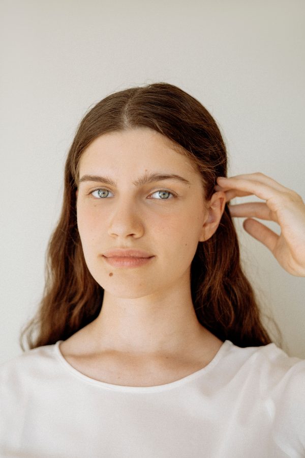Close-up portrait of a woman with long brown hair and a natural expression against a neutral background. Mobile 4K