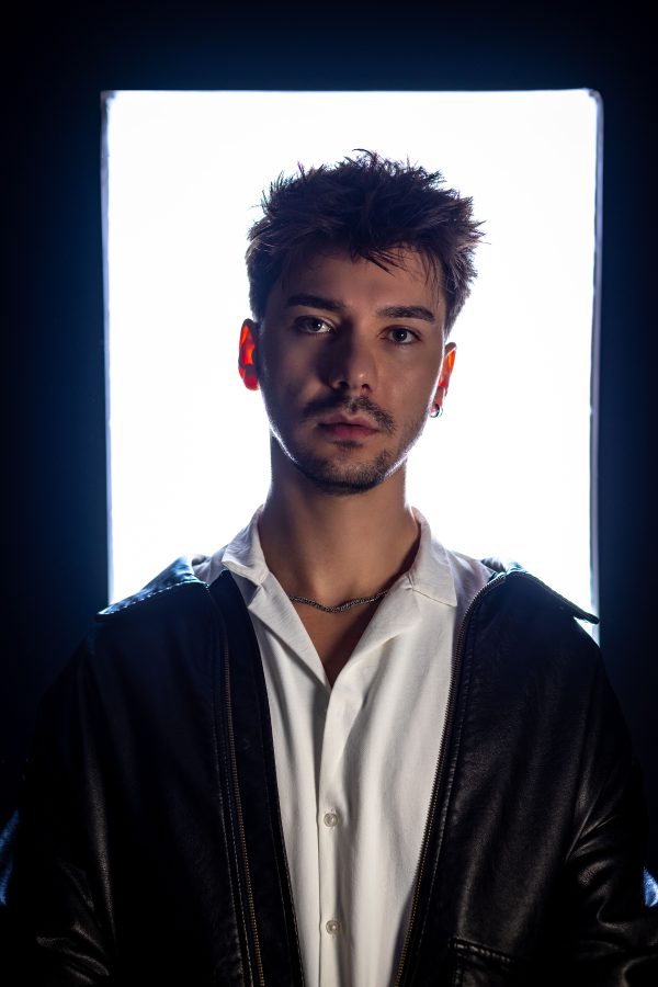 Close-up portrait of a young man in dramatic lighting, showcasing modern style. Mobile 4K
