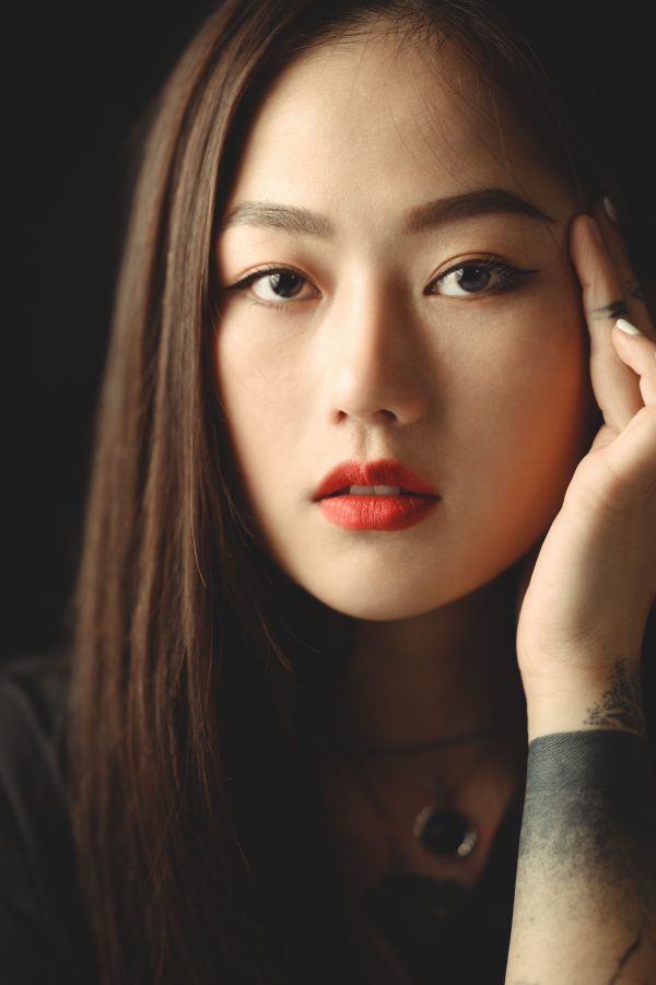 Close-up portrait of an Asian woman with bold makeup and tattoo in Ho Chi Minh City. Mobile 4K