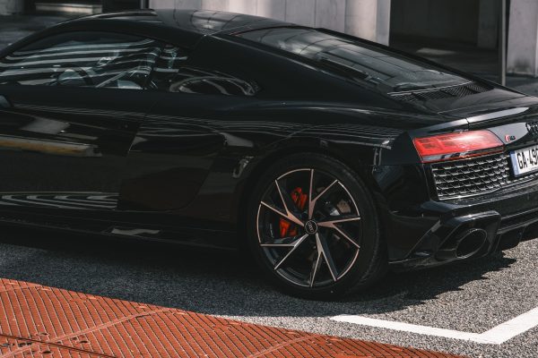 Close-up shot of a black luxury sports car with distinctive taillight and stylish wheels. Voitures 4K