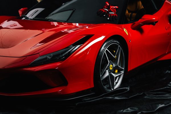 Close-up shot of a sleek red sports car with branded gloves on the dashboard. Ideal for luxury automotive themes. Voitures 4K