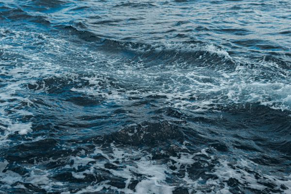 Close-up shot of swirling ocean waves and white foam, showing natural movement. Nature 4K