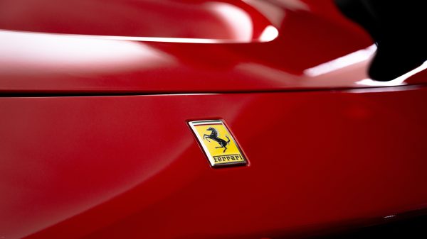 Close-up view of a shiny red sports car with emblem for luxury branding. Voitures 4K