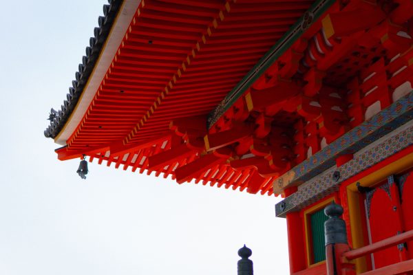 Close-up view of a vibrant red traditional Japanese temple roof with intricate wooden architectural design. Anime 4K