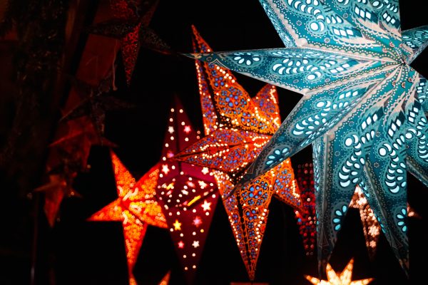 Colorful illuminated star-shaped lanterns glowing brightly against a dark night sky. Espace 4K