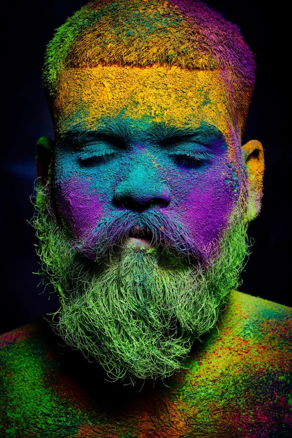 Colorful portrait of a man covered in vivid Holi powders with eyes closed, showcasing cultural festival art. Mobile 4K