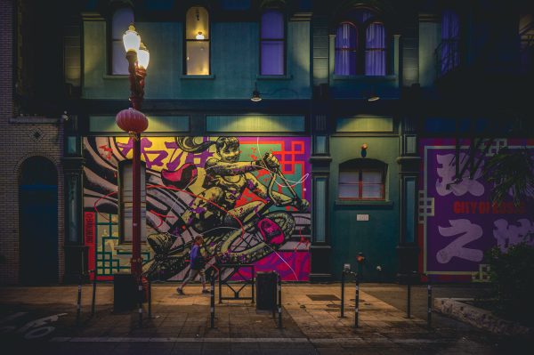 Colorful street mural on a city building exterior at night with streetlights. Manga 4K