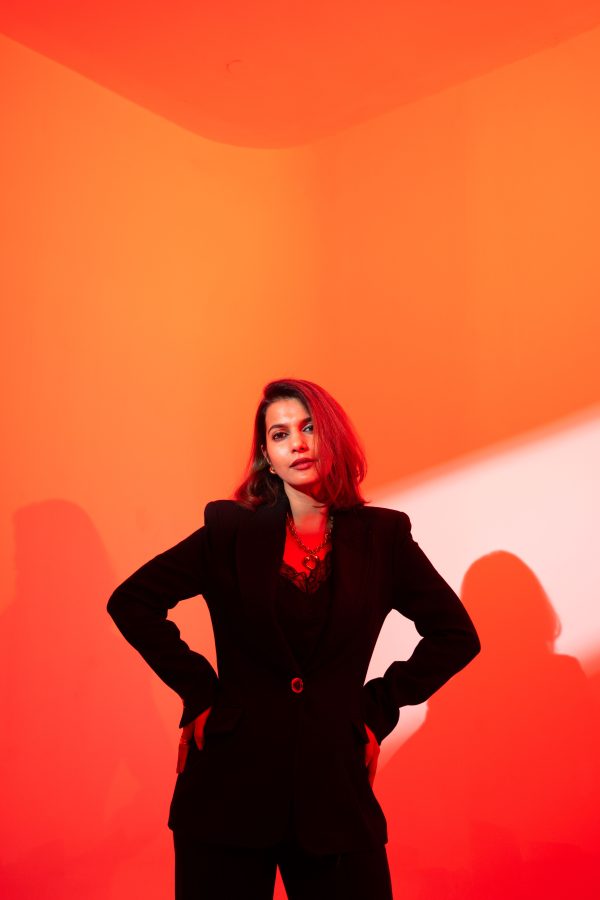 Confident woman in a black outfit posing against vibrant red background with dramatic lighting Mobile 4K