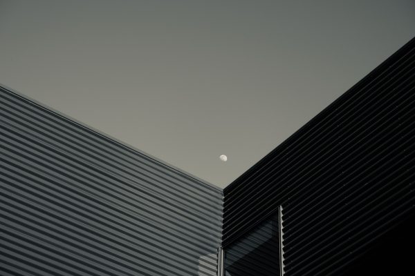 Contemporary building facades with a visible moon in the clear evening sky. Minimaliste 4K