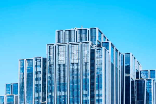 Contemporary glass building under bright daylight with clear blue sky backdrop. Architecture 4K