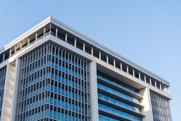 Contemporary highrise building with glass facade under a clear blue sky. Architecture 4K