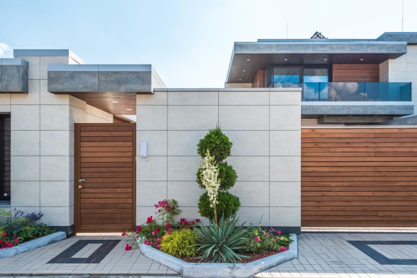 Contemporary house exterior featuring a stylish wooden facade, entrance gate, and vibrant garden. Nature 4K
