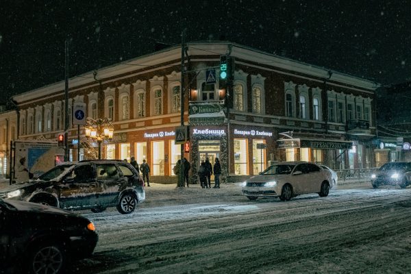 Cozy winter street scene at night with snowfall in a city intersection. Voitures 4K