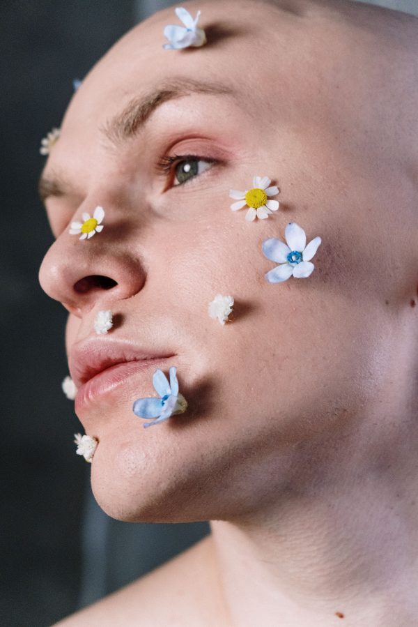 Creative close-up portrait of man with floral makeup. Artistic expression with delicate flowers. Mobile 4K