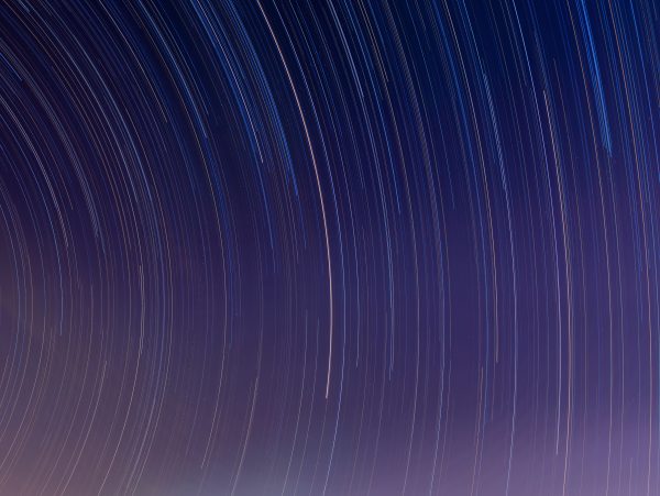 Curved star trails captured in a long exposure night sky, showcasing celestial movement.