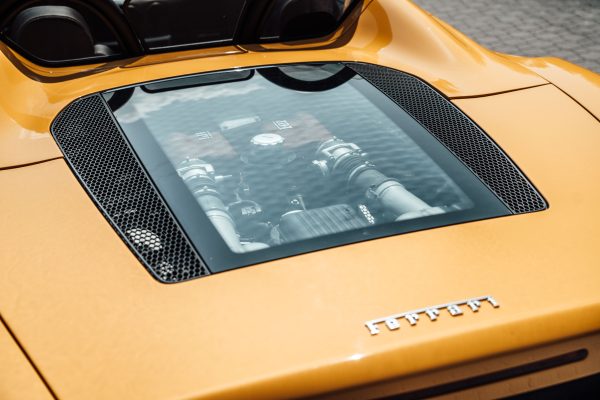 Detailed close-up of a Ferrari engine under a sleek yellow hood, highlighting modern design. Voitures 4K