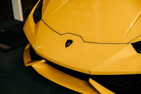 Detailed close-up of a sleek yellow Lamborghini hood with iconic emblem. Voitures 4K