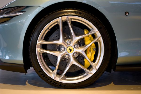 Detailed image showcasing a Ferrari's alloy wheel with yellow brake calipers highlighting design and engineering. Voitures 4K