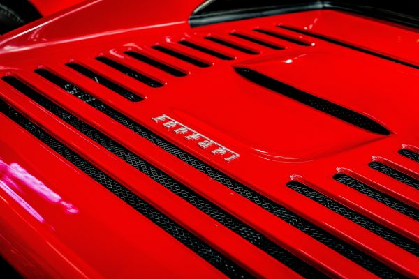 Detailed shot of a Ferrari emblem on a classic red sports car, showcasing luxury and automotive design. Voitures 4K