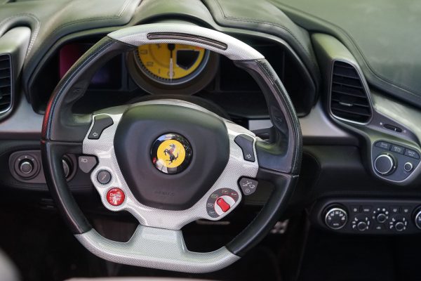 Detailed view of a Ferrari sports car steering wheel with dashboard controls in focus. Voitures 4K