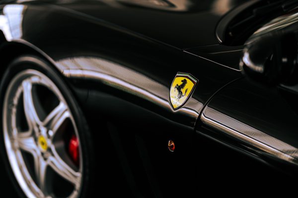 Detailed view of a luxury sports car highlighting its sleek curves and emblem. Voitures 4K